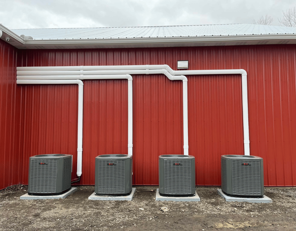 Four outdoor air conditioning condenser units installed against a building wall